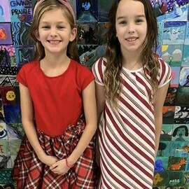Two young students wearing clothing that resembles candy canes.